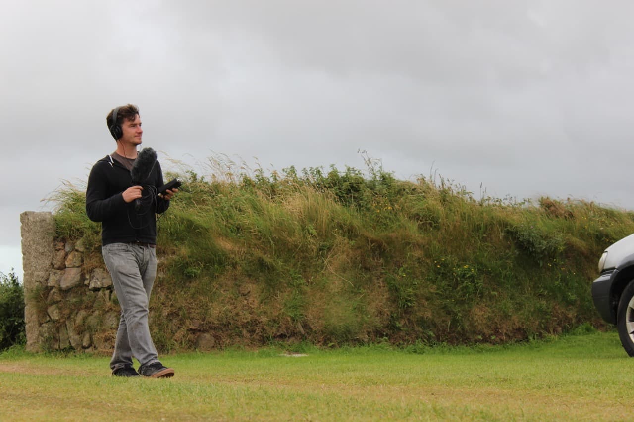 Recording location sound with a shotgun mic beside a stone wall